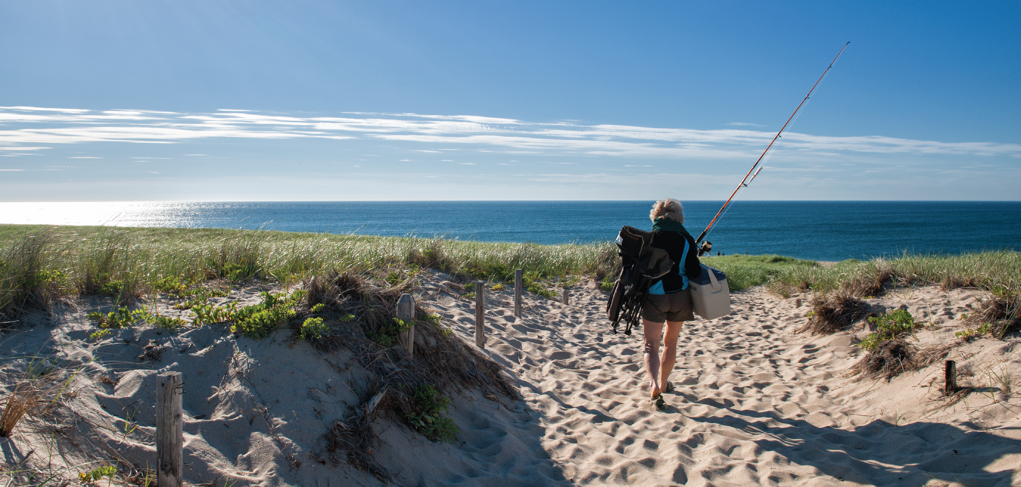 woman walking on beach to go fishing Cape Cod